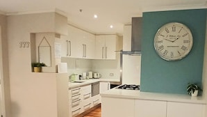 Una cocina moderna con armarios blancos, una estufa a gas y un reloj de pared.