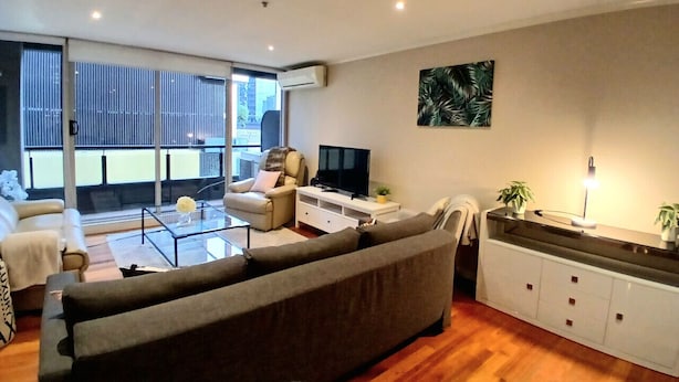 Una sala de estar moderna con un sofá, una mesa de centro, un televisor y un balcón con vistas.