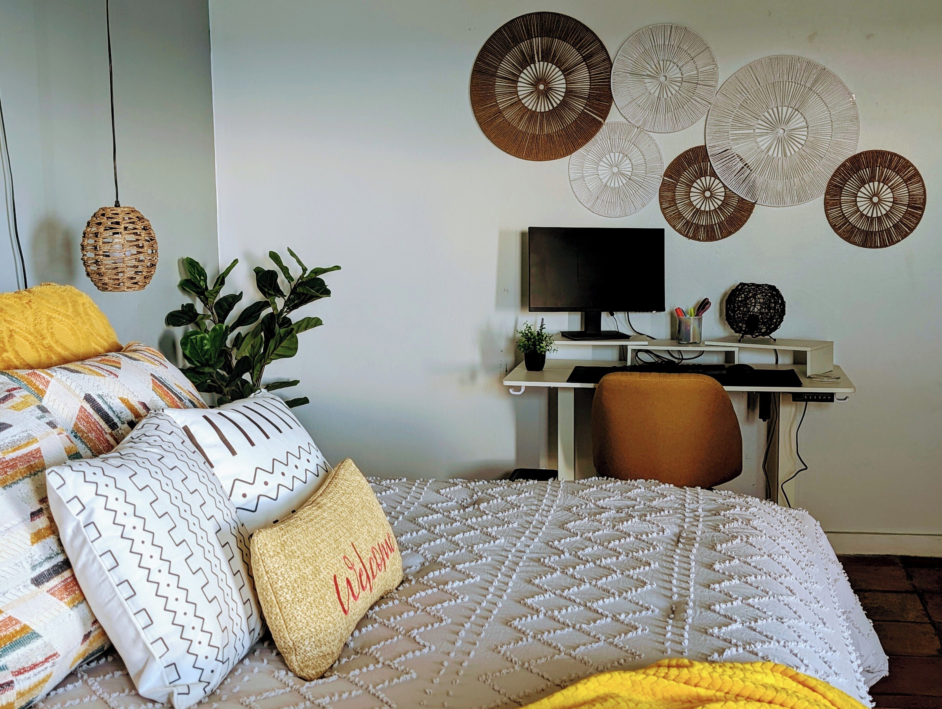 A bedroom with a bed, a desk, a chair, a TV, and decorative wall art.