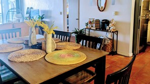 A dining area with a wooden table, woven placemats, and chairs. There is a vase with yellow flowers on the table. - "Spectacular Ocean Views" at Calypso Castillo! (Sion Farm)