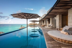 A infinity pool with a view of the ocean, outdoor seating, and a modern architectural design. - La Casa de la Playa All Inclusive Adults Only by Xcaret (Playa del Carmen)