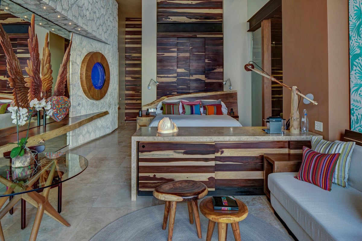 Ein modernes Interieur mit einer zentralen Holztheke, einer Couch, einem Couchtisch und einem Esstisch mit Glasplatte.