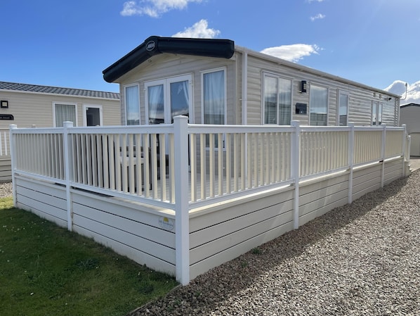 A mobile home with a white deck and a covered porch area.