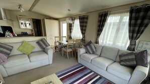 Ein Wohnzimmer mit zwei Sofas, einem Couchtisch, einem Esstisch und einer Küchenzeile mit einer Mikrowelle.