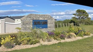 Ein Steinschild mit der Aufschrift 'Silver Sands Holiday Park', umgeben von pflegeleicht angelegten Blumenbeeten mit verschiedenen Pflanzen.