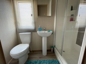 A compact bathroom with a toilet, sink, and shower.