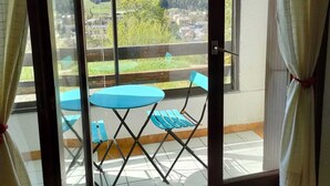 Un balcón con mesa y sillas, con vistas a un paisaje montañoso.