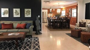 Uma sala de estar ampla, com sofá, mesa de centro e área de jantar com cadeiras e mesa.