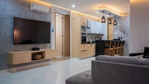 A modern living room with a flat-screen TV, wooden cabinets, and a grey sofa. - Vallarta Sunset Condo with Pool (Puerto Vallarta)
