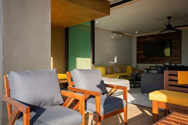 Una sala de estar moderna con muebles de madera, un sofá amarillo y un televisor de pantalla plana montado en la pared.