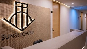 A reception desk with a tiled wall and a logo that reads "SUNSET TOWER". - Sunny Puerto Vallarta Condo (Puerto Vallarta)