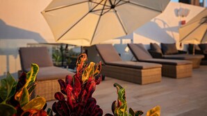 A rooftop lounge area with multiple lounge chairs and large umbrellas. - Sunny Puerto Vallarta Condo (Puerto Vallarta)