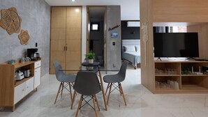 A modern living room with a dining area, a TV, and a kitchen visible through an open door. - Studio w/ Stunning Rooftop Pool (Puerto Vallarta)