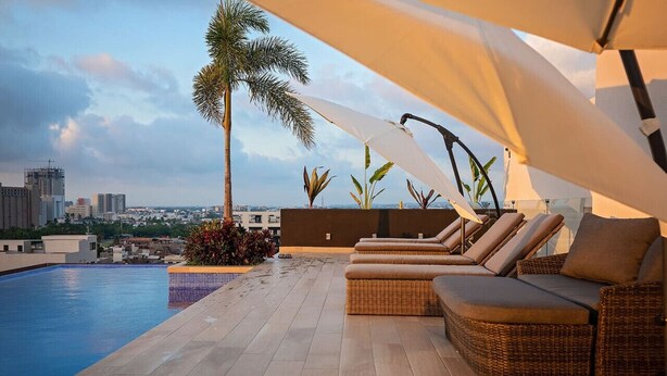 A rooftop pool area with lounge chairs and a view of the city skyline. - Studio w/ Stunning Rooftop Pool (Puerto Vallarta)