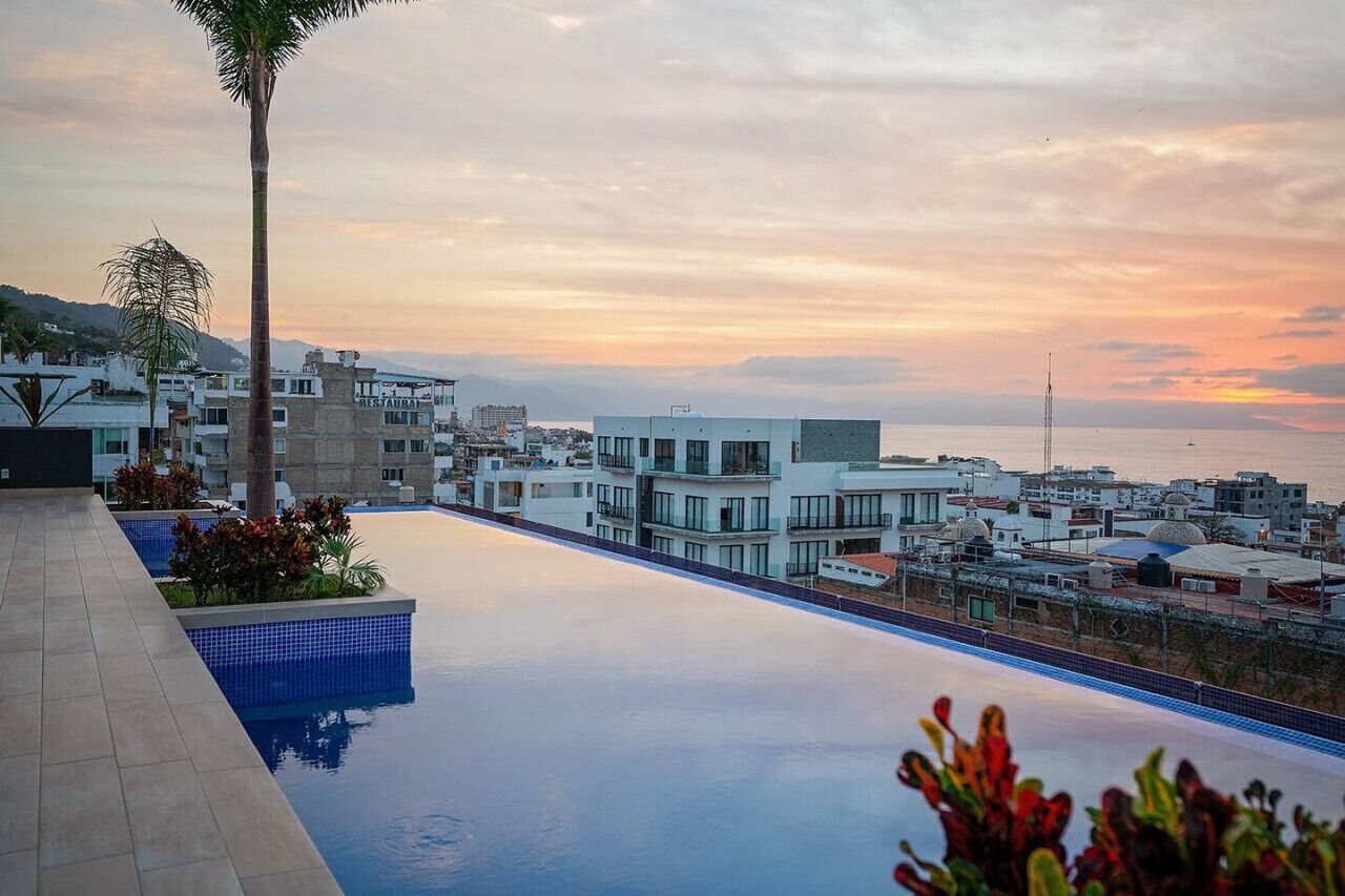 Une piscine sur le toit offrant une vue sur le paysage urbain de la côte au coucher du soleil.
