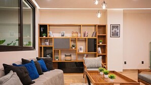 A modern living room with a grey sofa, wooden bookshelves, and a coffee table. - Vallarta City View Condo w/ Pool (Puerto Vallarta)
