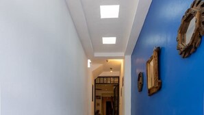 Un couloir avec un mur d’accent bleu, un sol carrelé et des spots encastrés au plafond.