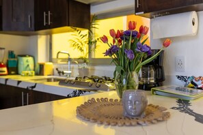 A kitchen with dark cabinets, a gas stove, and a vase of tulips on the counter.