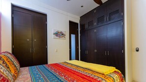 Quarto com uma cama grande, armários de madeira escura e edredom colorido com padrão.