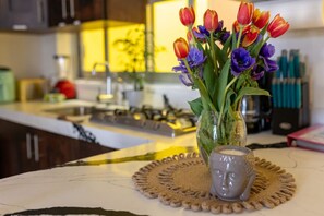 Een keukentafel met een vaas tulpen en een kaars.