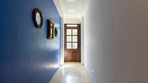 Um corredor com parede azul, porta de madeira e uma janela.