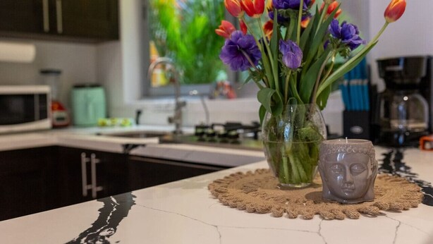 A kitchen counter with a vase of tulips and a candle.