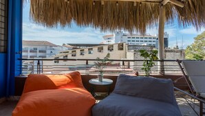 A balcony with two bean bags, a small table with a plant, and a view of buildings in the background.