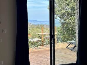 A room with a view of a wooden deck, a table, and a chair.
