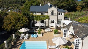A large house with a swimming pool, outdoor seating, and a garden.