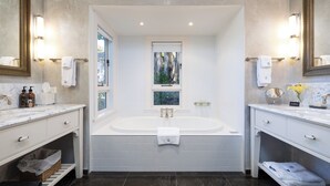 A modern bathroom with a large bathtub, two sinks, and a window with a view. - Pihopa Retreat (Nelson)