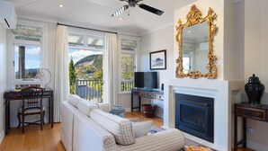 Un salon avec une cheminée, un téléviseur, un grand miroir et une vue sur l’extérieur.