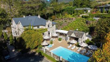 A large house with a swimming pool, outdoor seating, and a garden.