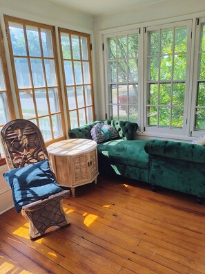 A room with a green upholstered bench, a wooden chair with a patterned cushion, and a small round table. - Spacious 7-bedroom house across from University and close to Downtown Lock Haven (Lock Haven)