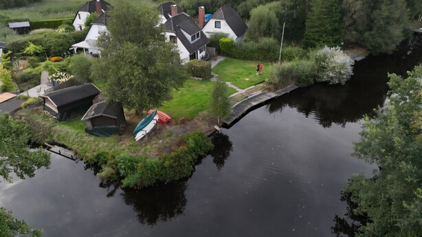 Een dorp aan de rivier met huizen, een brug en boten.