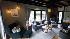 Een gezellige woonkamer met een bank, fauteuils, een salontafel en een open haard.