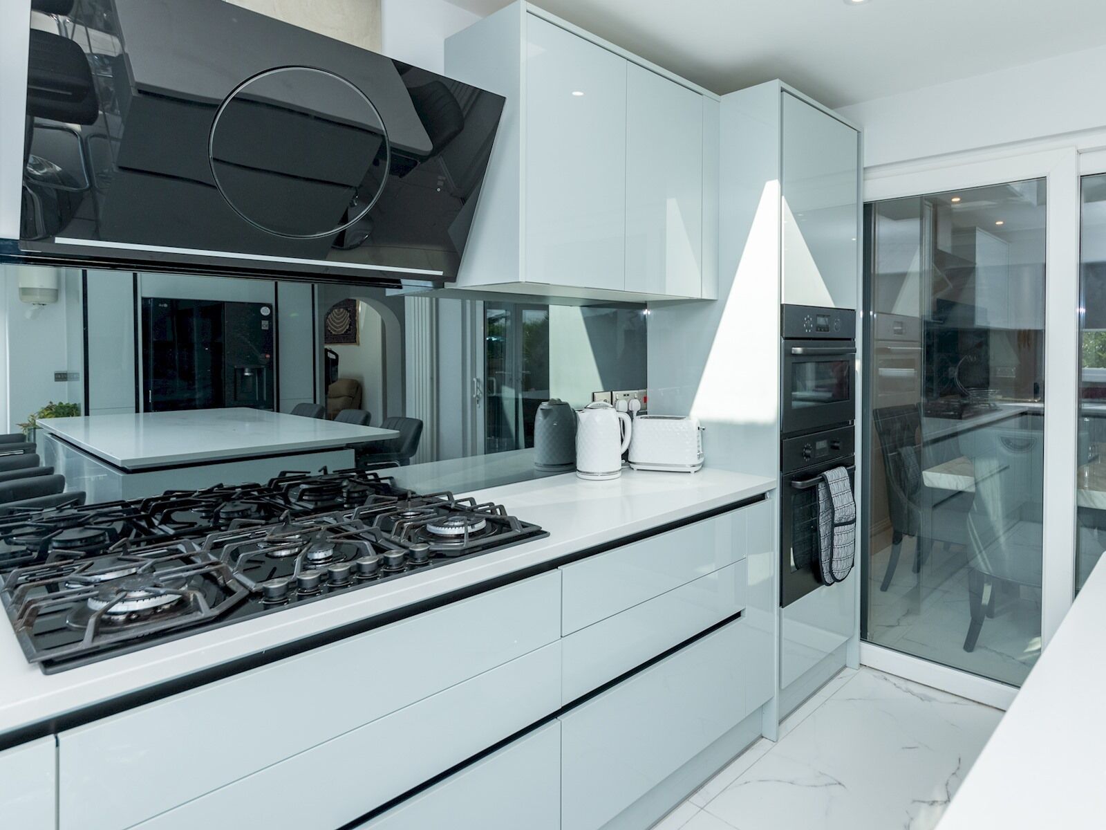 A modern kitchen with a gas stove, white cabinets, and a large window.