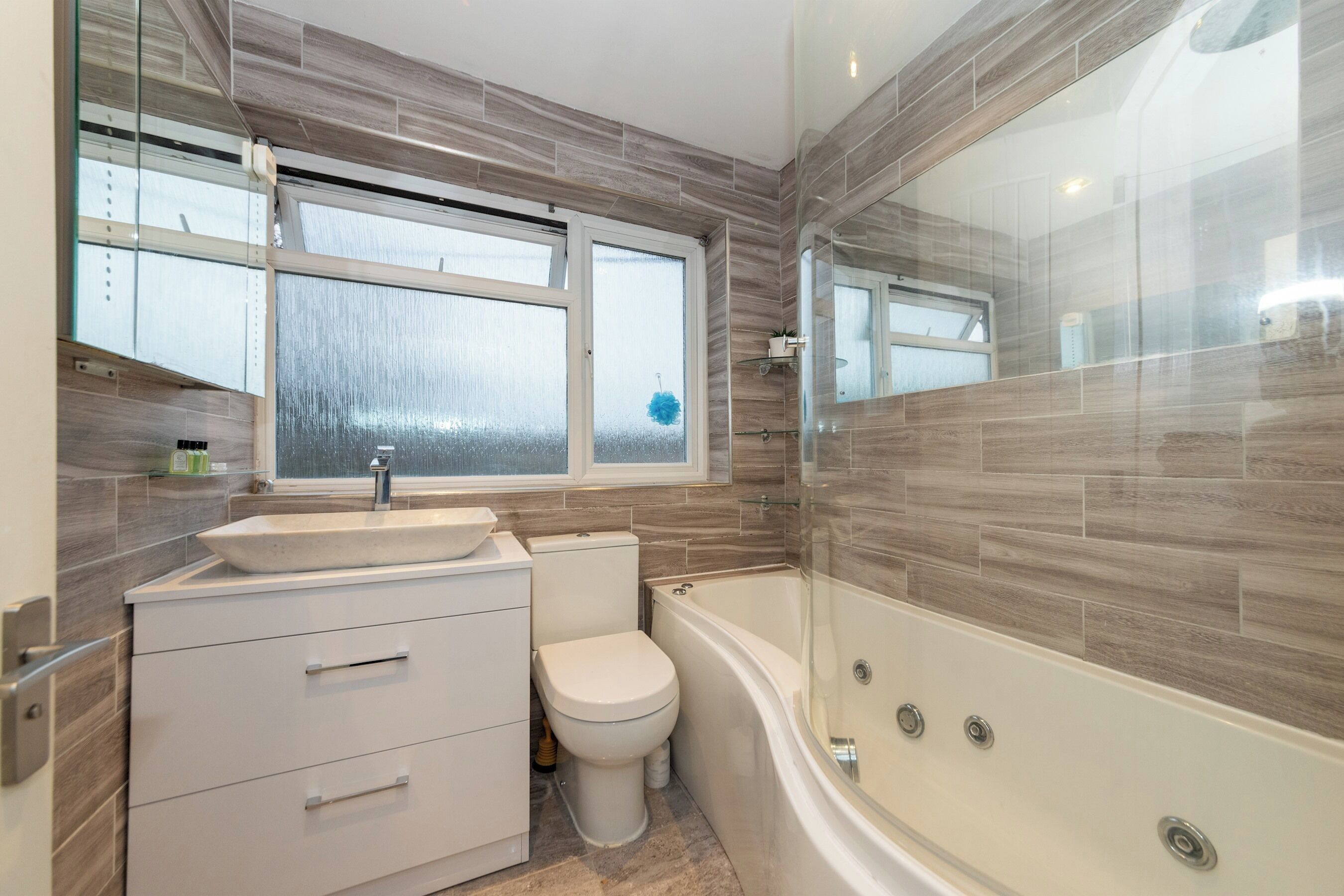 A modern bathroom with a large bathtub, a toilet, and a sink.
