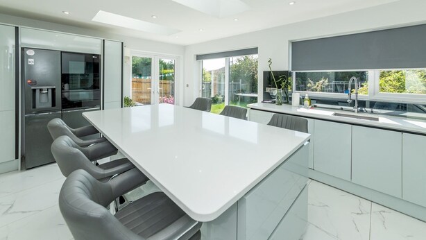 A modern kitchen with a large island, built-in appliances, and large windows offering views of the outdoors.
