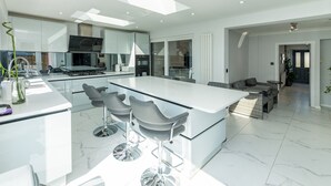 A modern kitchen with a central island, bar stools, and a dining area with a sofa and table.