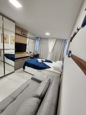 Une chambre d’hôtel moderne dotée d’un grand lit, d’un canapé, d’une télévision et d’un coin repas.