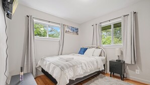 Une chambre à coucher avec un lit, une table de chevet et une fenêtre avec des rideaux.