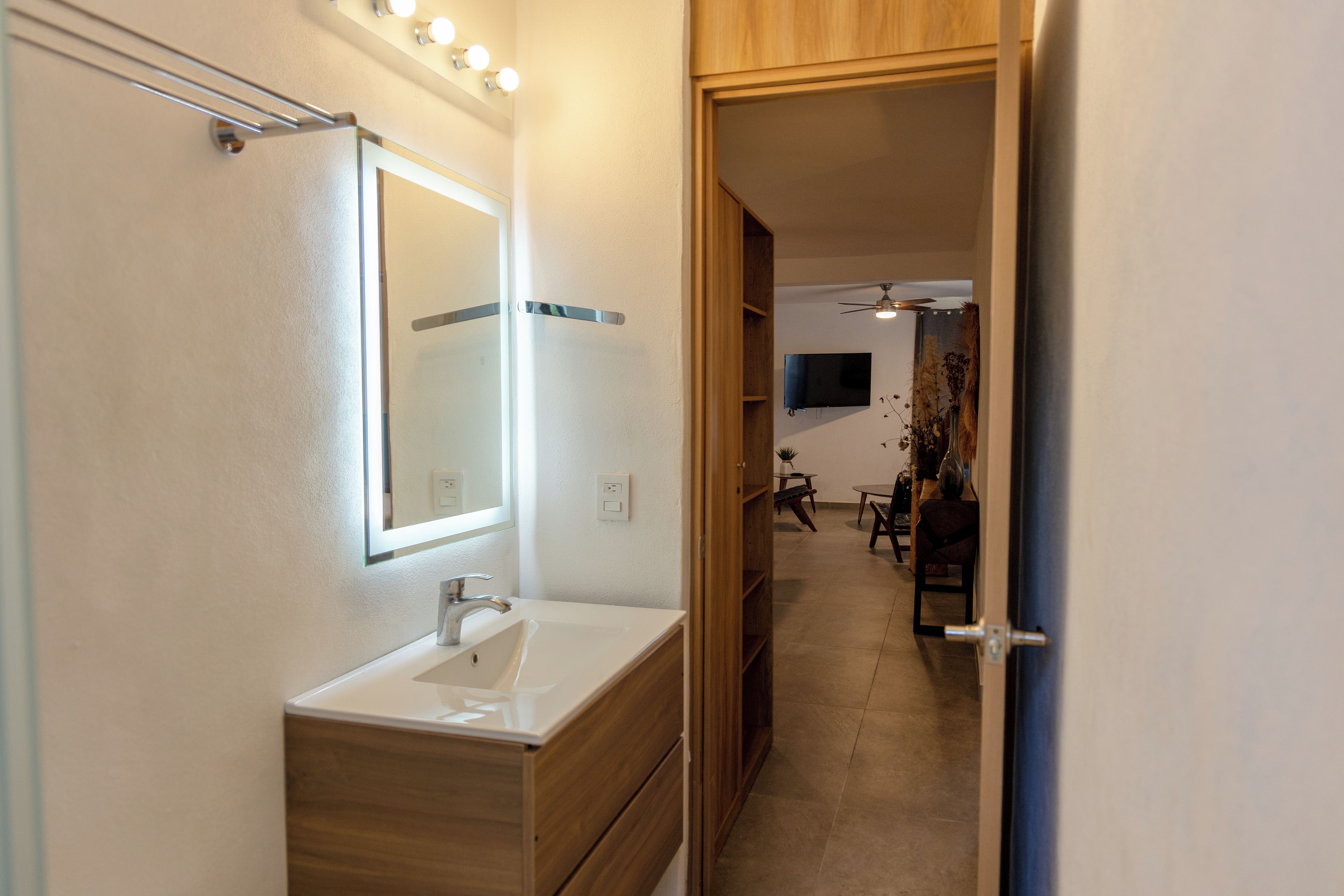 A bathroom with a white sink, a mirror, and a vanity cabinet.