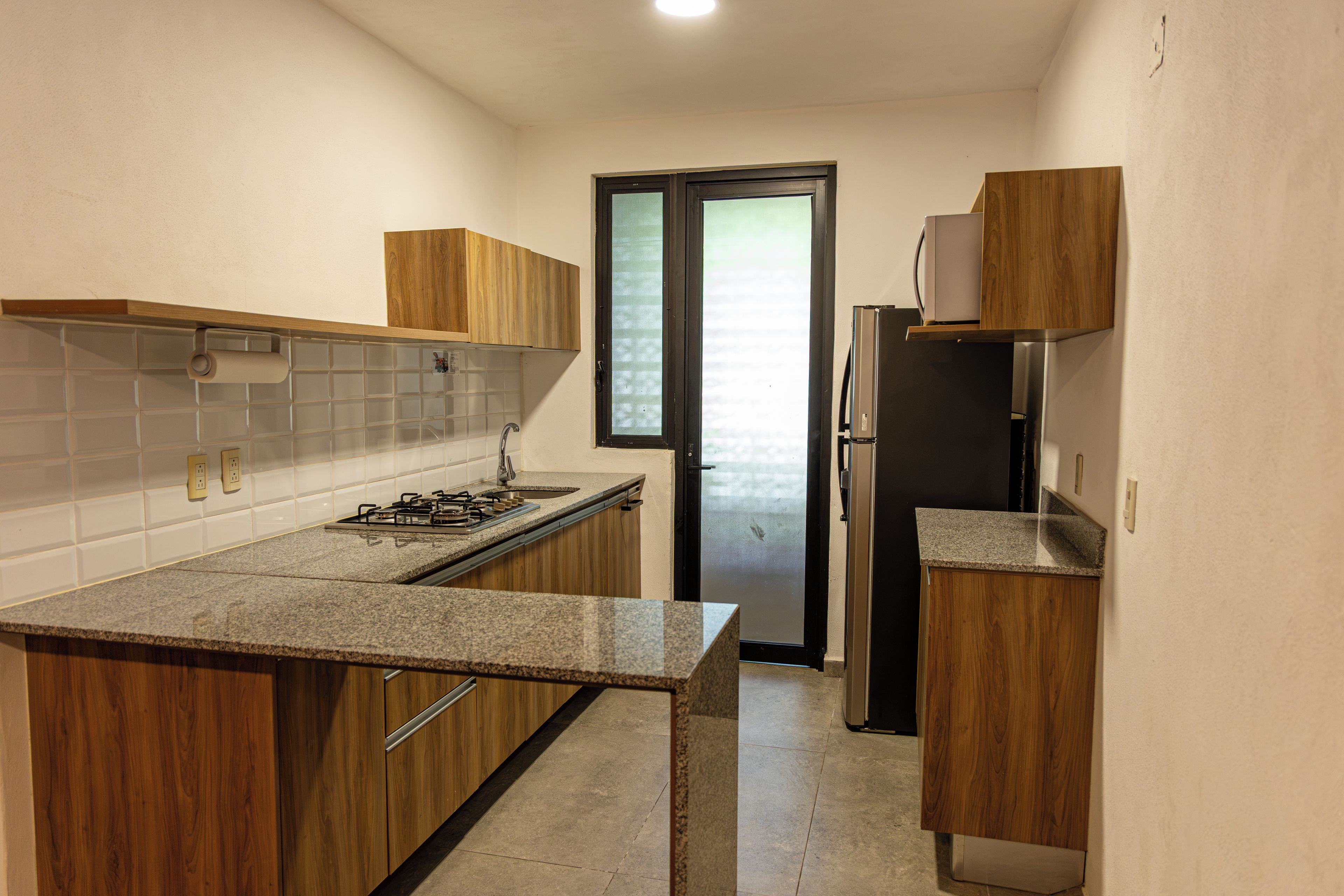 Una cocina funcional con armarios de madera, un refrigerador de acero inoxidable y una estufa a gas.