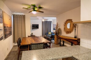 A dining area with a wooden table and chairs, a ceiling fan, and a television mounted on the wall. - SAN LUISITO (Puerto Vallarta)
