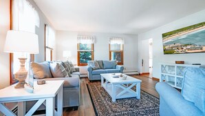 A living room with two sofas, a coffee table, and a TV mounted on the wall.