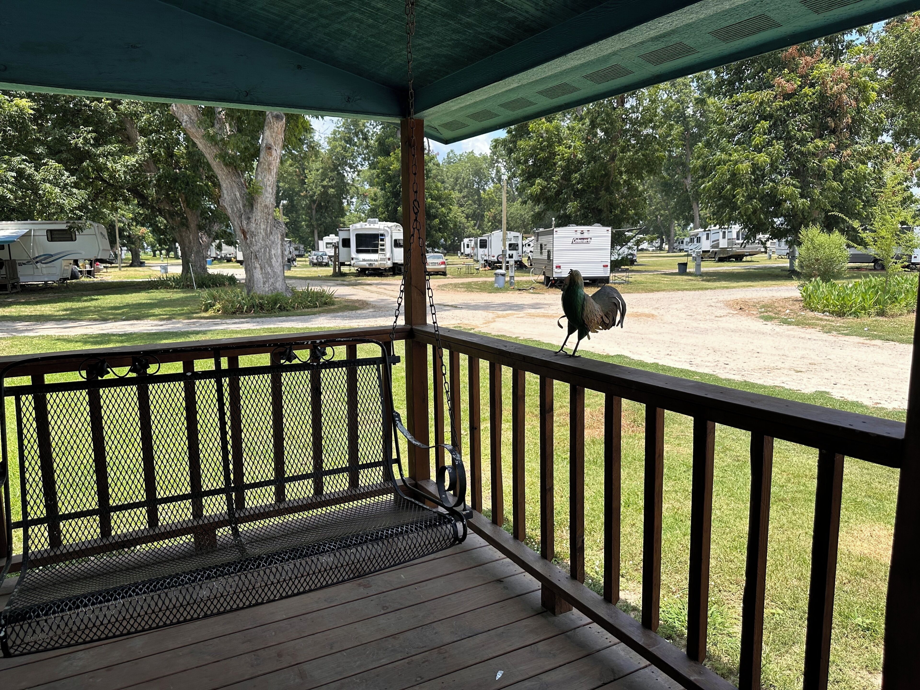 A covered porch with a view of a campground.