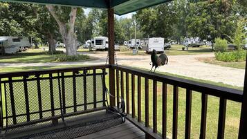 A covered porch with a view of a campground.