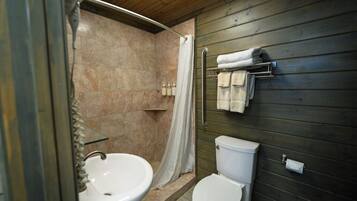 A bathroom with a sink, toilet, and shower area.