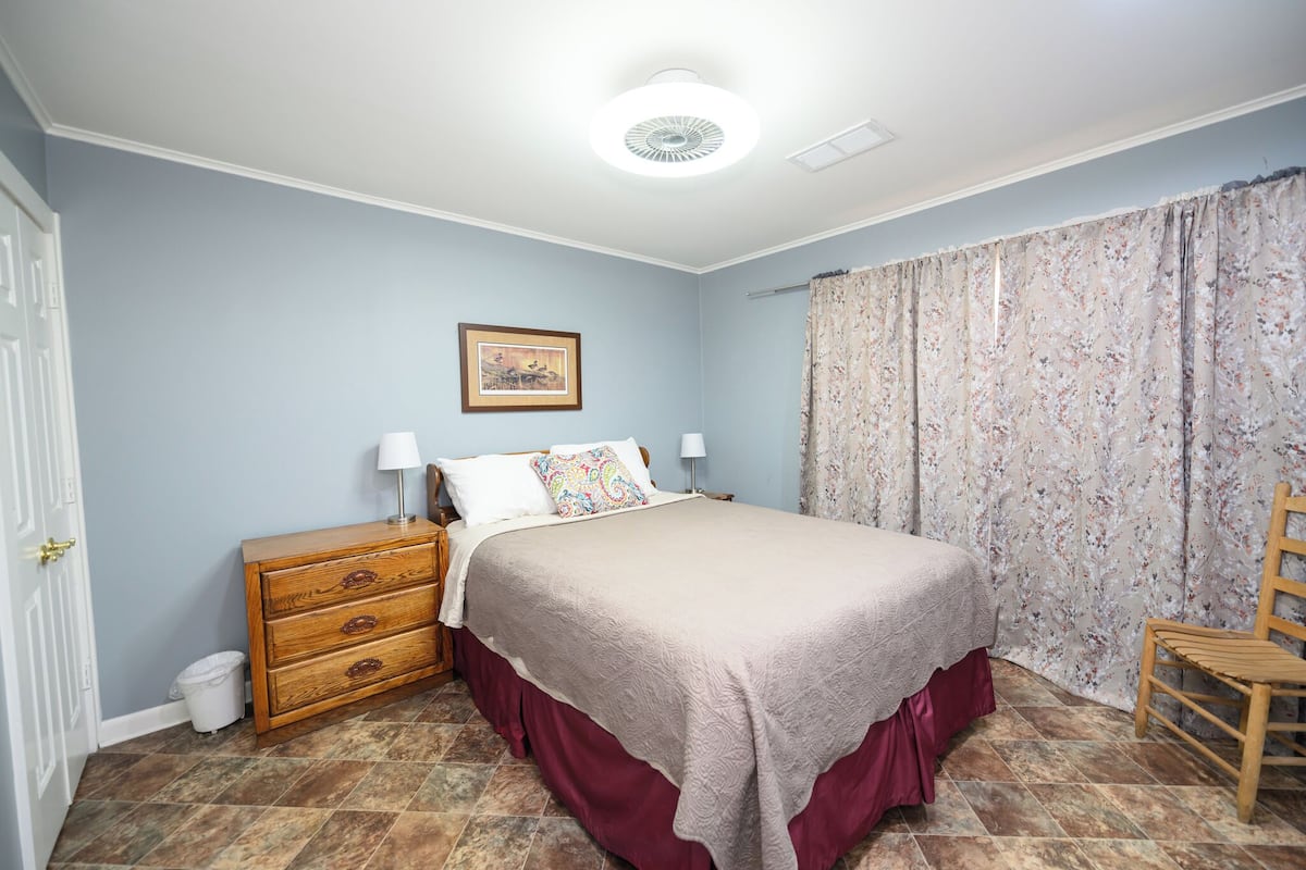 Ein Schlafzimmer mit Bett, Schminktisch, Stuhl und einem Bild an der Wand.