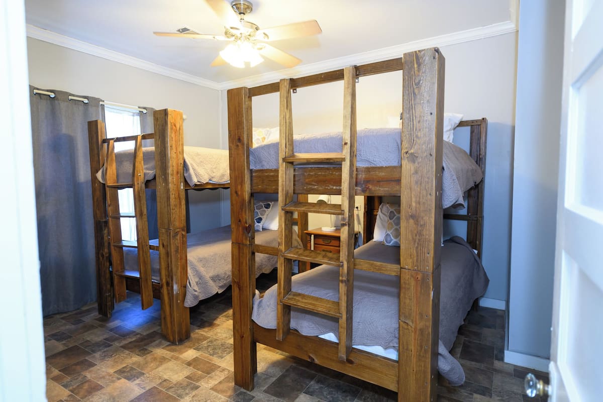 Ein Zimmer mit Etagenbetten, Deckenventilator und Fliesenboden.